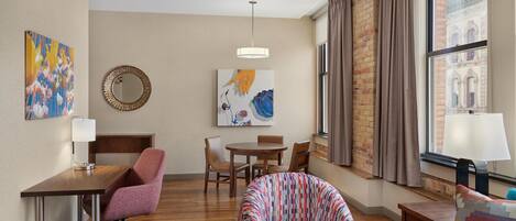 Une chambre d’hôtel moderne avec un plancher en bois, une table ronde, un canapé, une chaise et un lit.