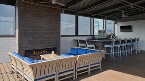 Un espacio al aire libre con área de estar, chimenea, bar y varias sillas.