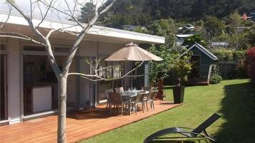 A patio with a table and chairs, a covered area with a table and chairs, and a lawn with a lounge chair.