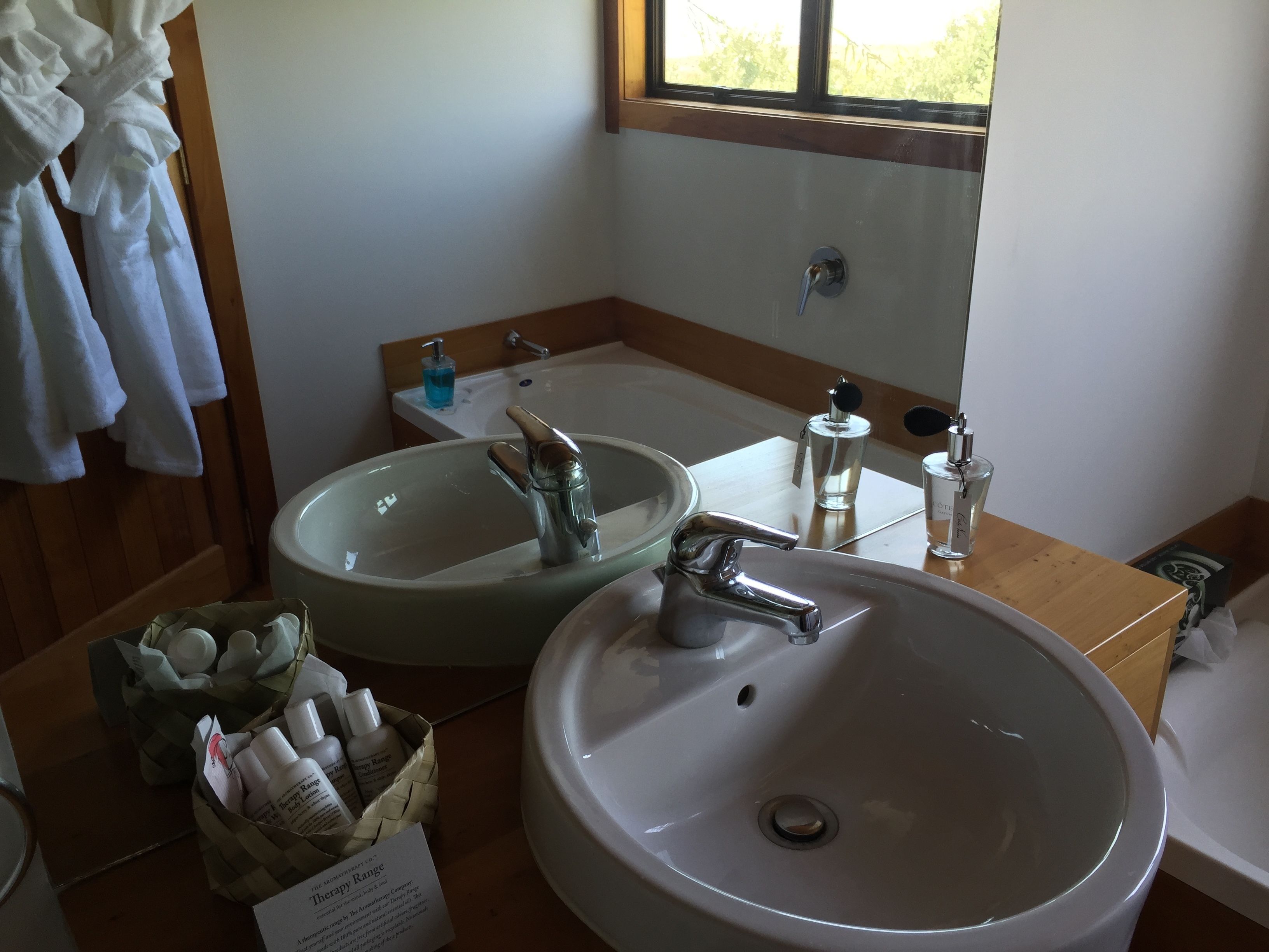 A bathroom with two sinks, a bathtub, and a window.