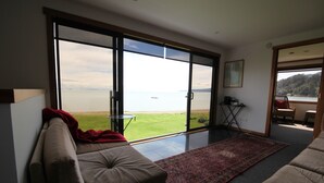 Ein geräumiges Wohnzimmer mit einer großen Schiebetür zu einem Balkon mit Blick auf ein Gewässer.