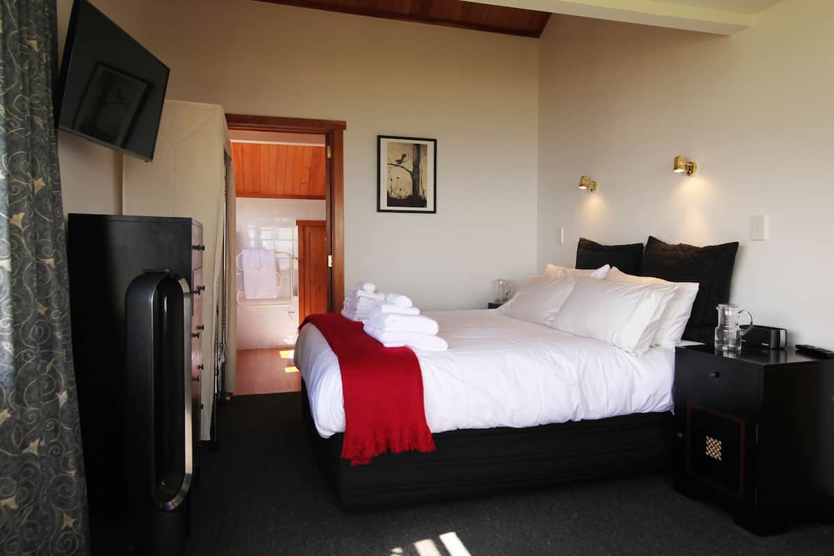 A hotel room with a bed, bedside table, and a television mounted on the wall.