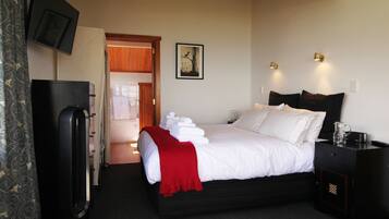 A hotel room with a bed, bedside table, and a television mounted on the wall.