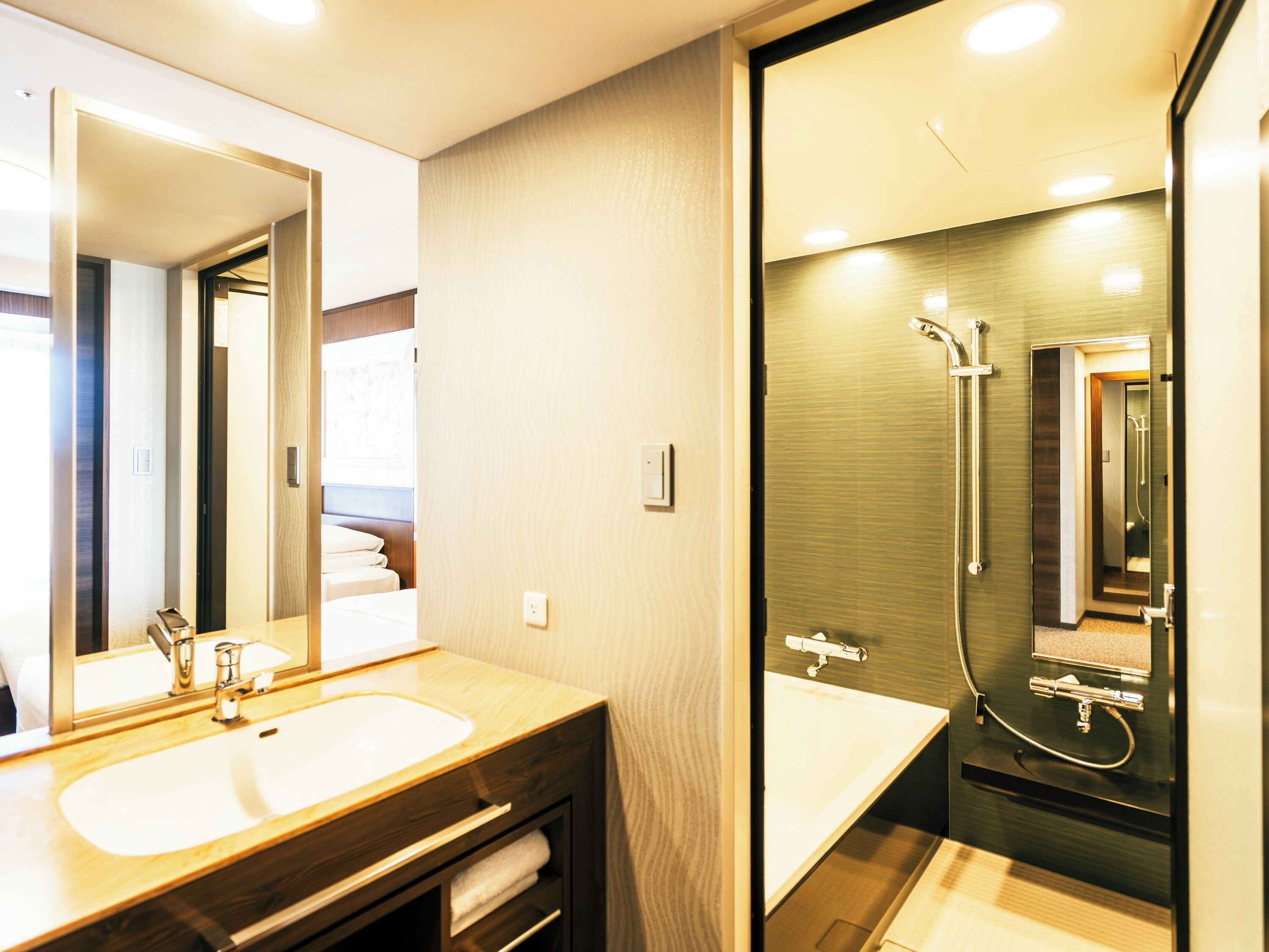 Ein modernes Badezimmer mit einem Holzwaschtisch, einem großen Spiegel, einer Duschkabine mit Glastür und einer sichtbaren Toilette im Hintergrund.
