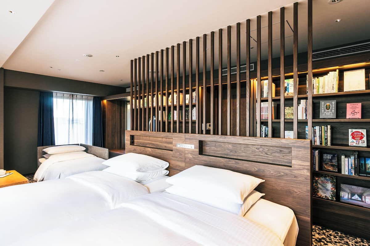 Un hotel moderno con una cama grande, una estantería de madera y vistas a la ciudad.