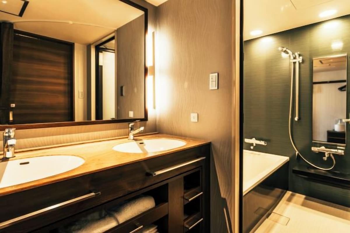 Une salle de bain moderne avec deux lavabos, un grand miroir et un espace douche.