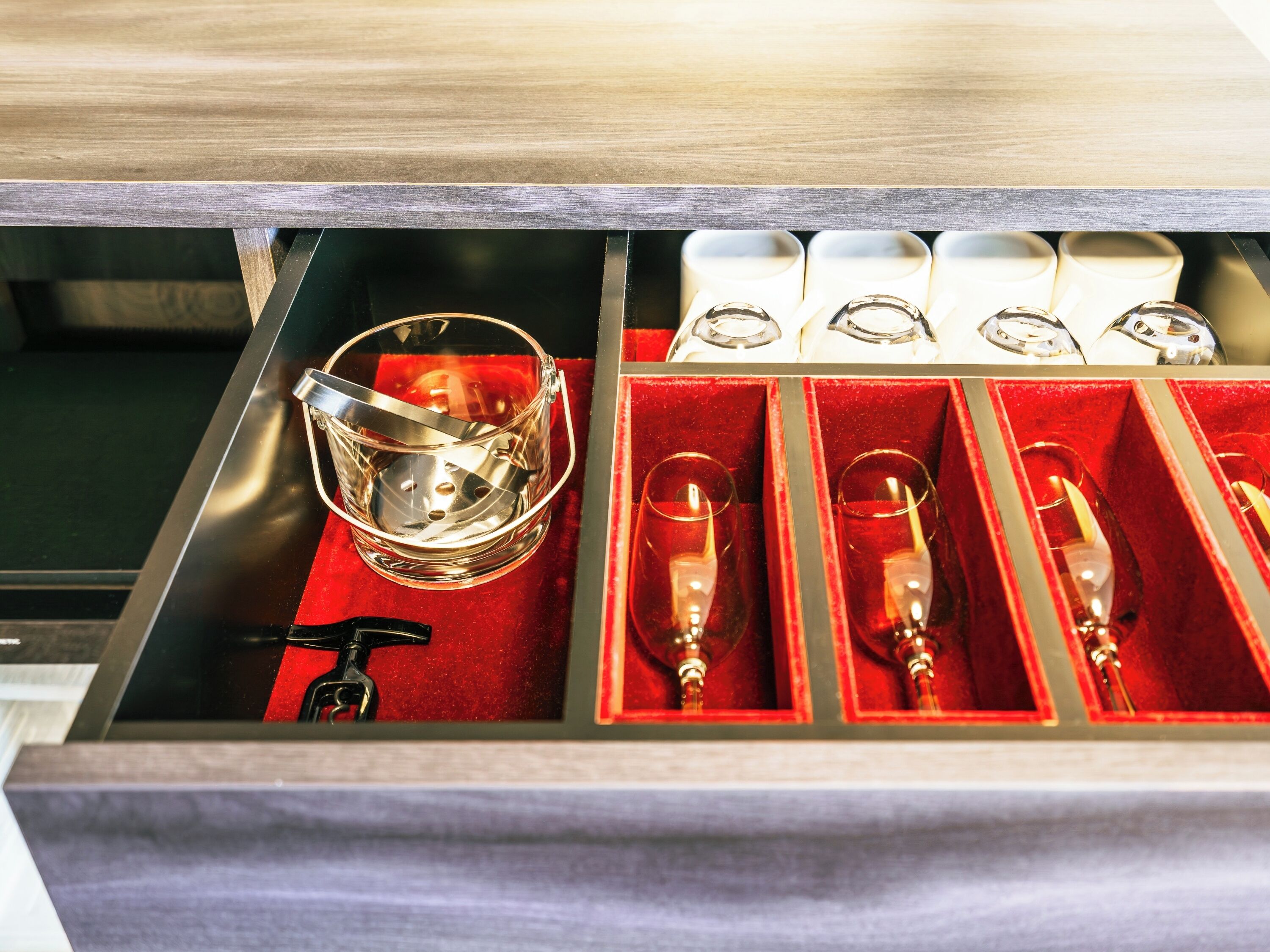 A drawer with a metallic bucket and several glasses.