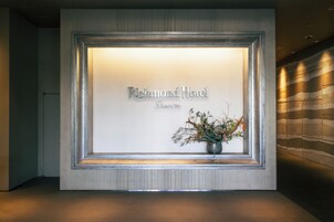 Aula, jossa on seinällä kehystetty kyltti, jossa lukee ”Richmond Hotel Premier”, sekä maljakko, jossa on kukkia.