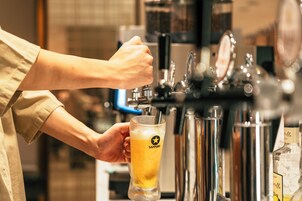 A hand holding a glass with a logo, a tap, and a bottle.