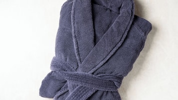 A folded dark blue bathrobe on a plain surface.