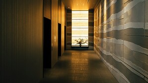 Un couloir avec un mur orné de motifs et une fenêtre au fond.