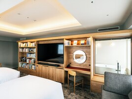 Una camera d'albergo con una grande televisione, scaffali in legno, una scrivania e un ampio specchio.