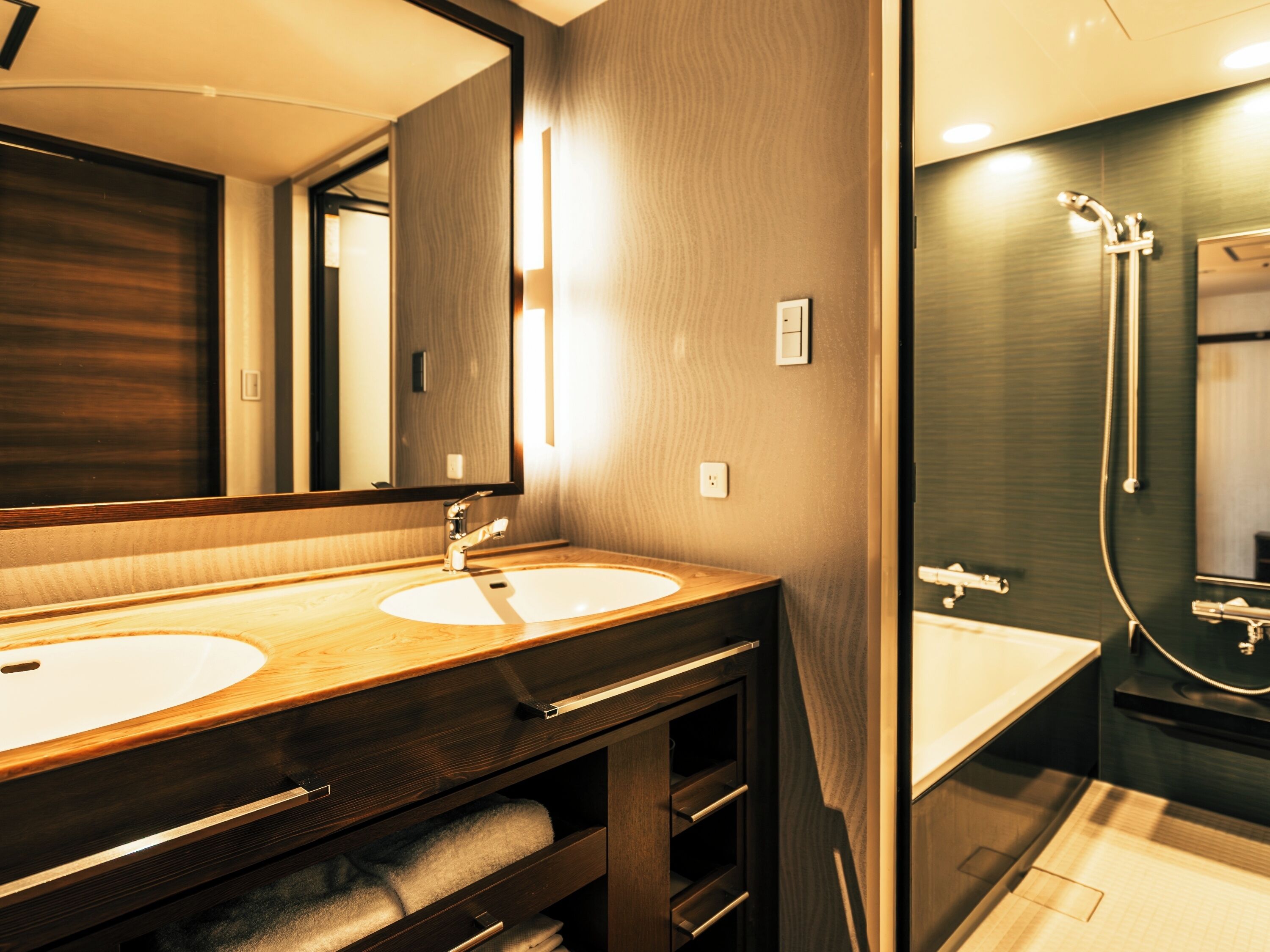 Un baño moderno con dos lavamanos, ducha y un espejo grande.