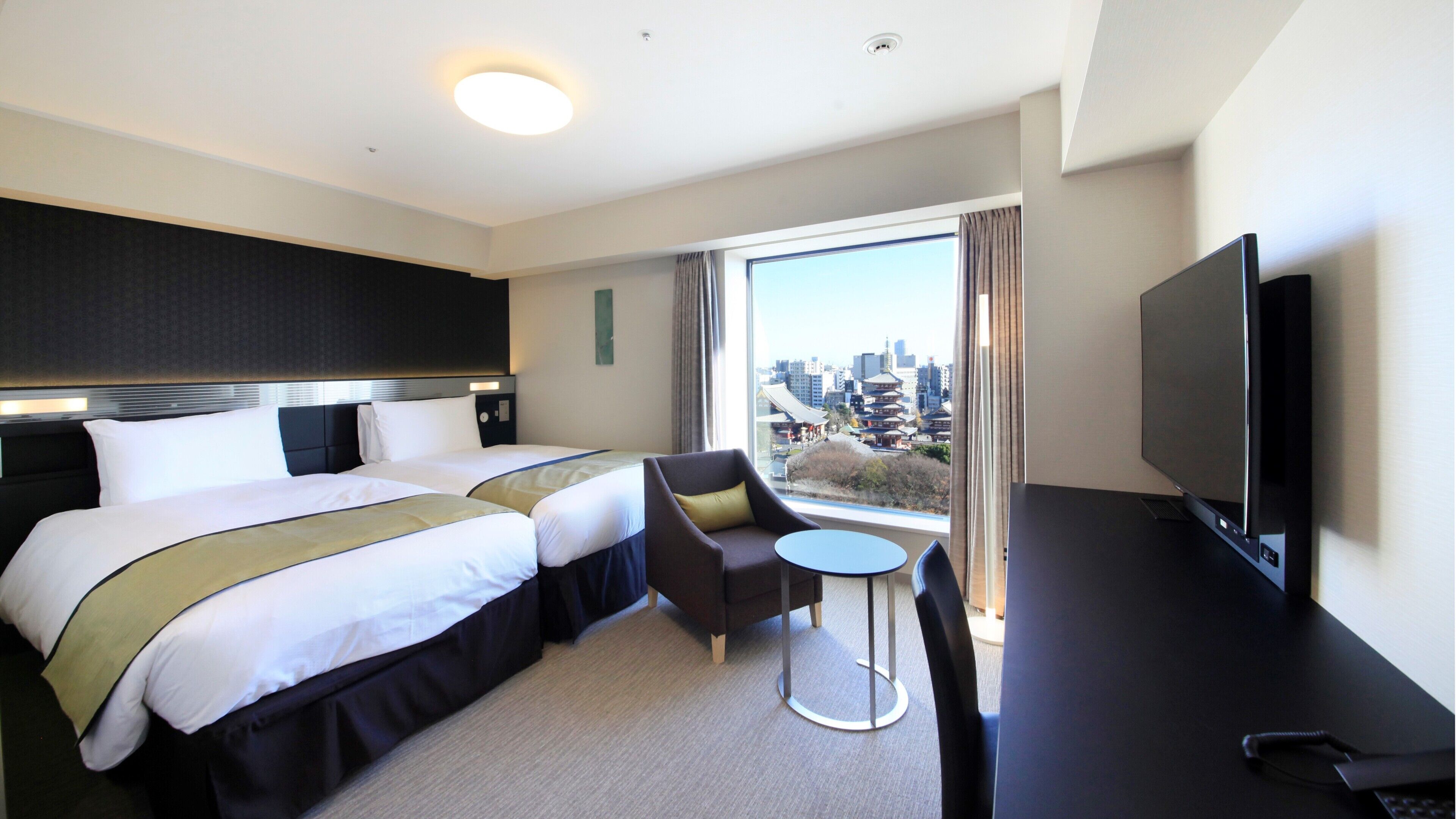 A hotel room with a bed, a TV, a small table, and a chair.