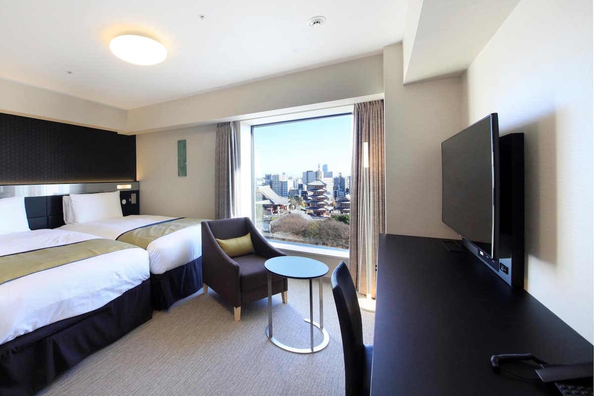 A hotel room with a bed, a TV, a small table, and a chair.