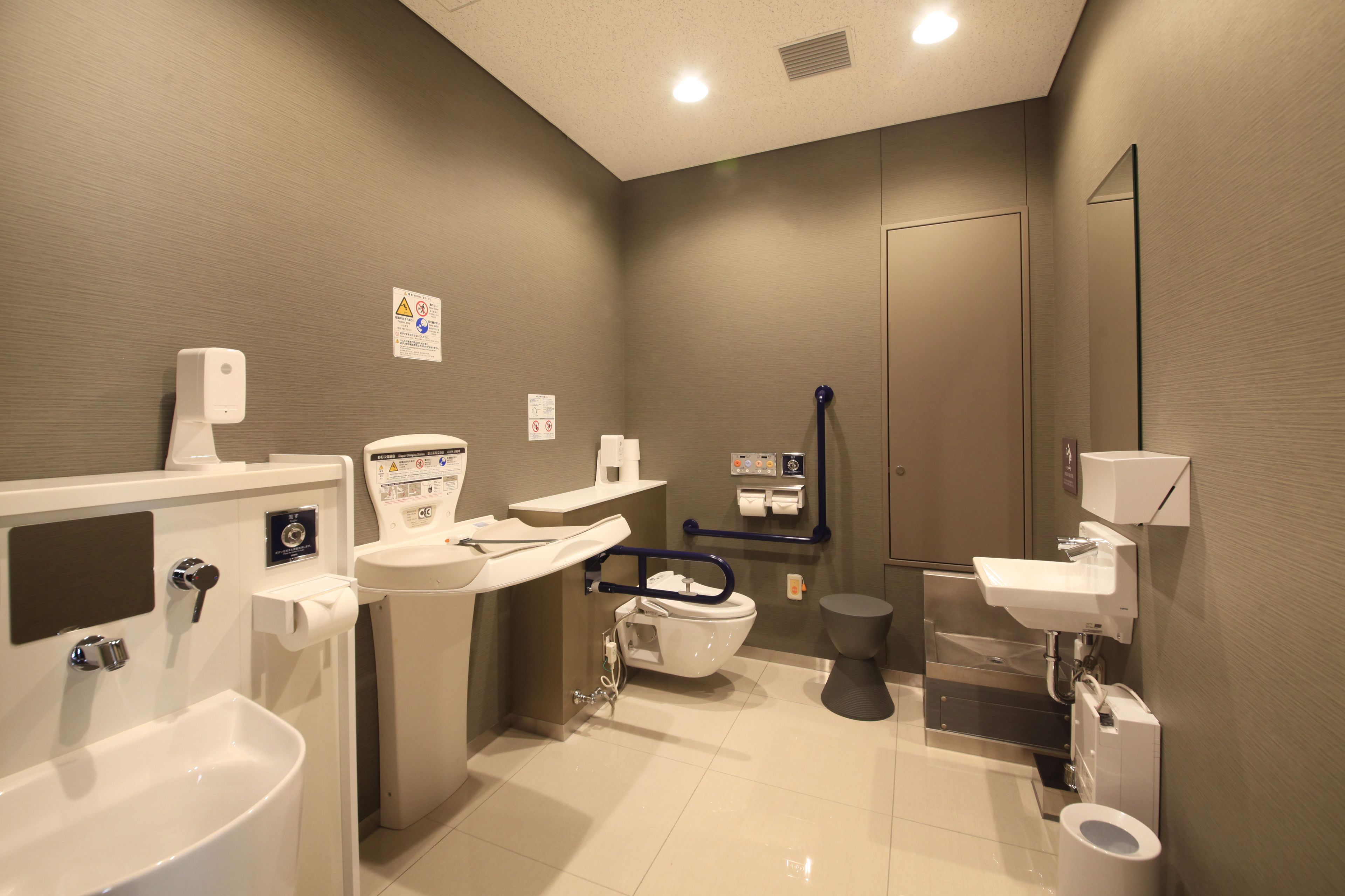 A modern bathroom with a bathtub, toilet, sink, and hand dryer.