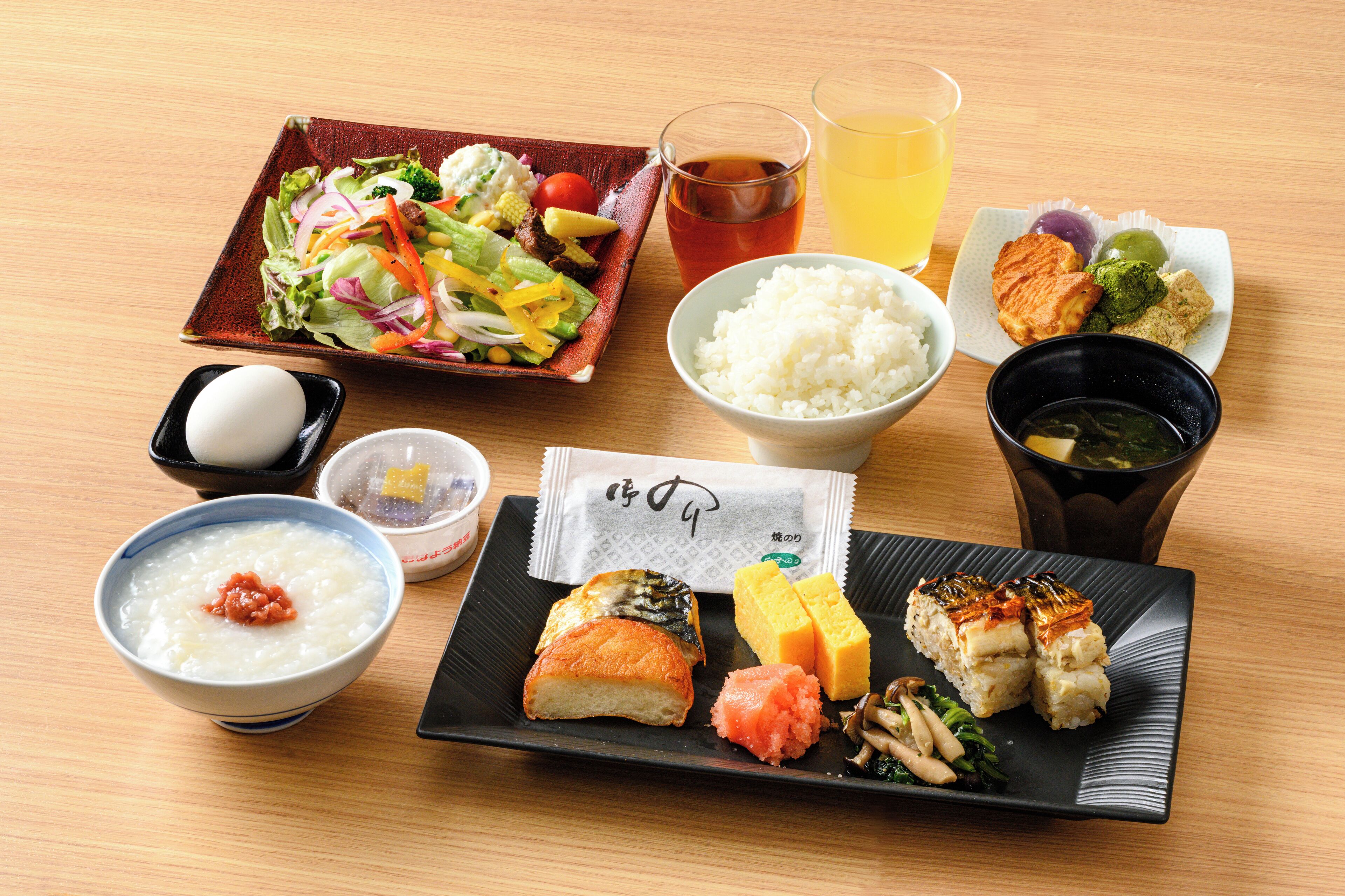 A variety of Japanese dishes including sushi, rice, and a salad, served on a wooden table.
