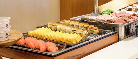 A buffet with various food items including sushi, sashimi, and other dishes.