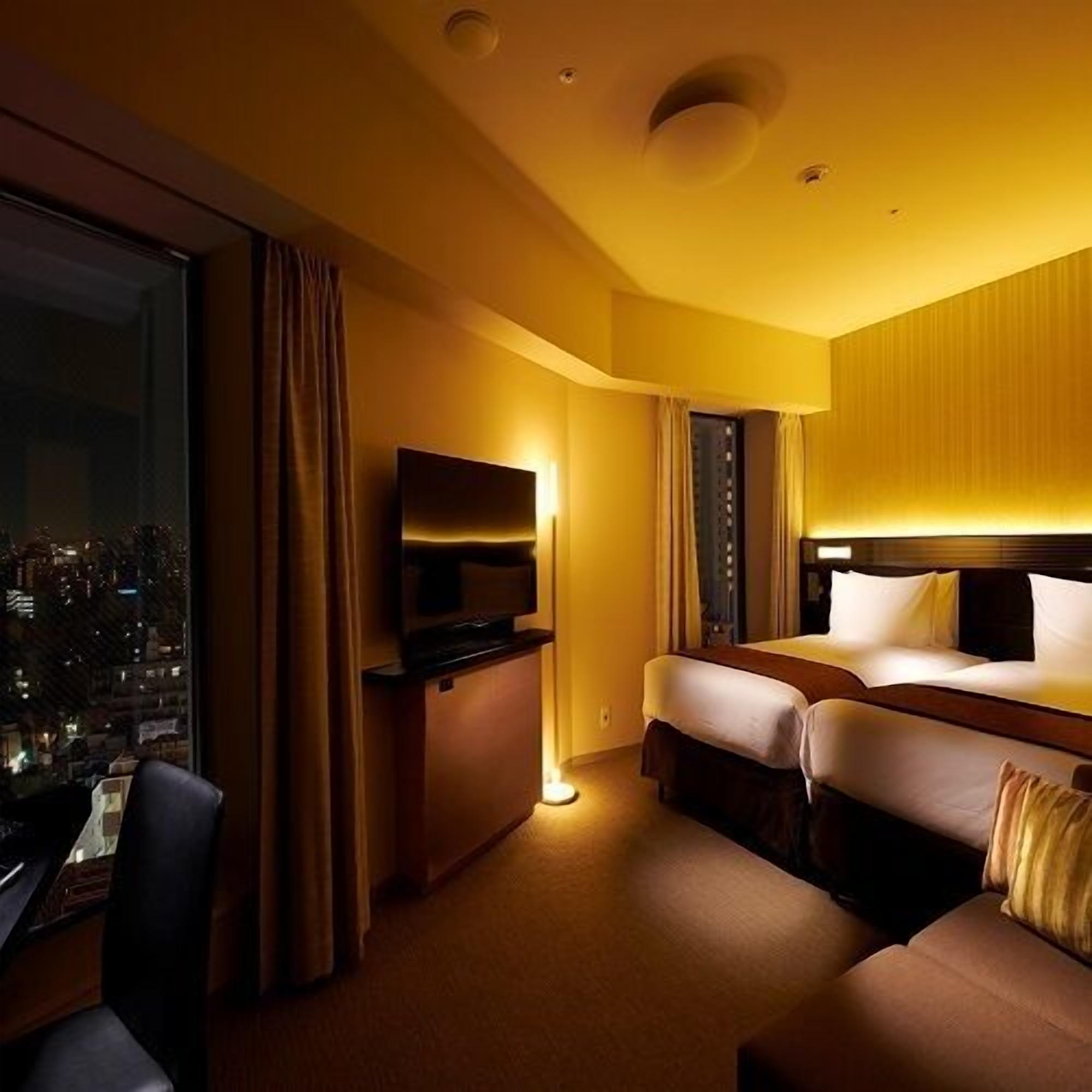 A hotel room with a city view, a bed, a desk, and a TV.
