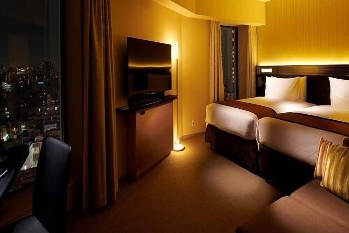Une chambre d’hôtel avec vue sur la ville, un lit, un bureau et un téléviseur.