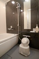 A modern bathroom with a bathtub, a shower, a toilet, and a mirror.