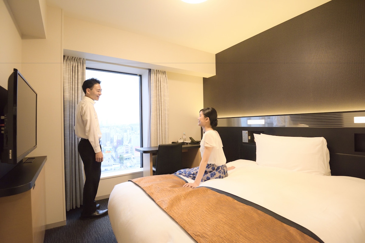 Una habitación de hotel con una cama grande, un escritorio y un televisor.
