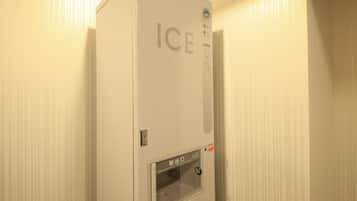 Una máquina de hielo blanca con la palabra “ICE” en la parte frontal, un panel de control con botones y una pequeña ventana.