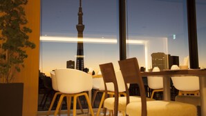 A dining area with a view of a city skyline, including a prominent tower, through large windows. - Richmond Hotel Premier Asakusa International (Tokyo)
