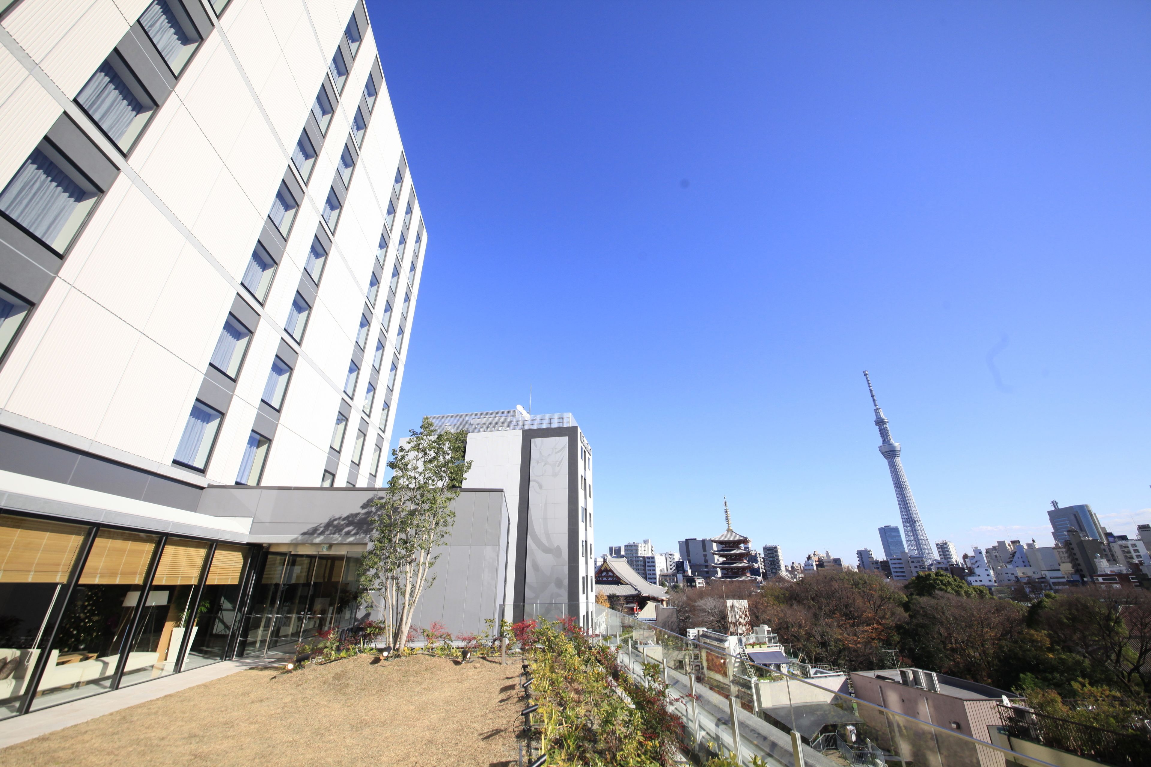 A modern building with large windows and a view of a cityscape including a tower.