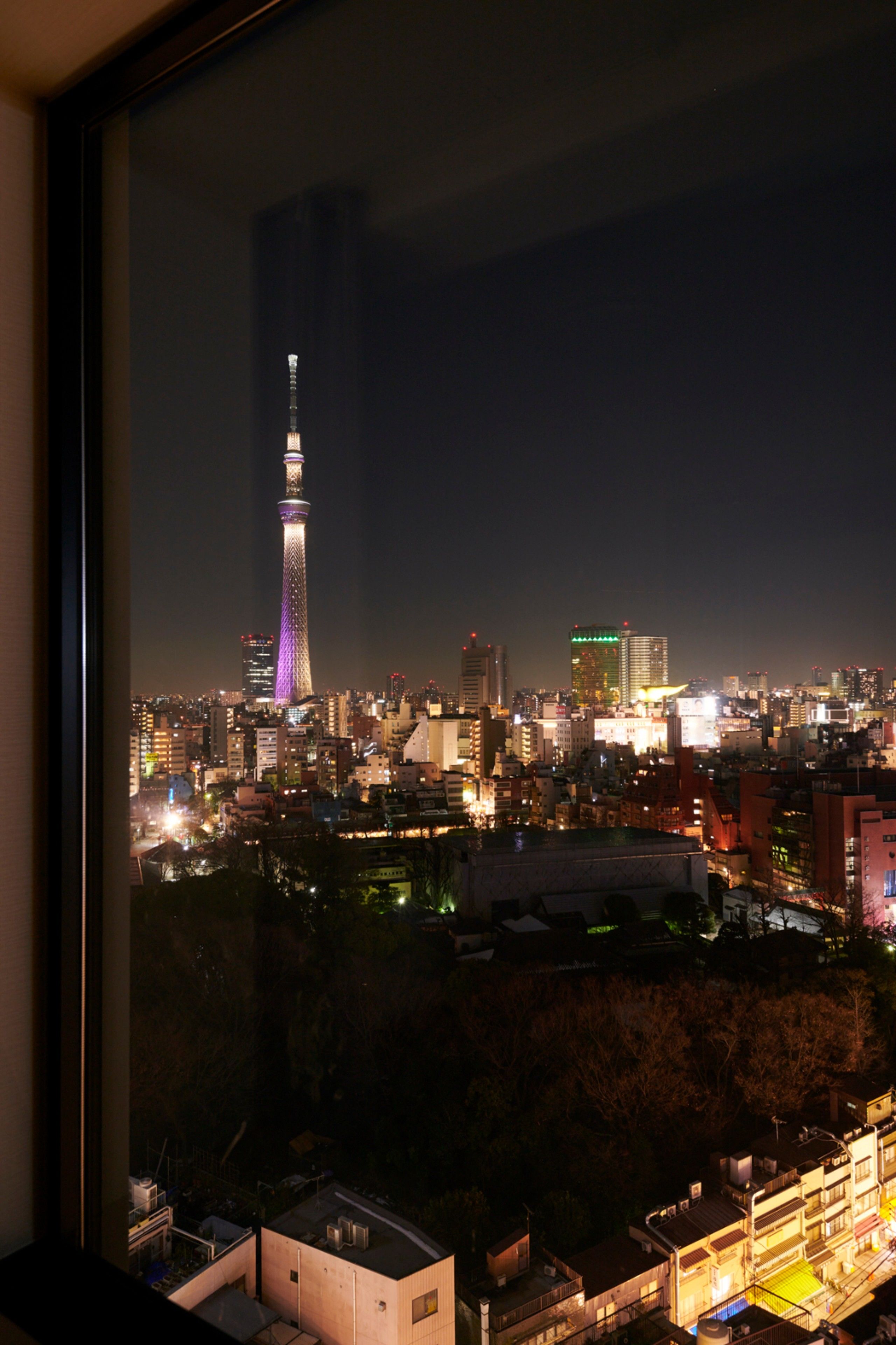 A nighttime cityscape with a prominent tower illuminated in purple.