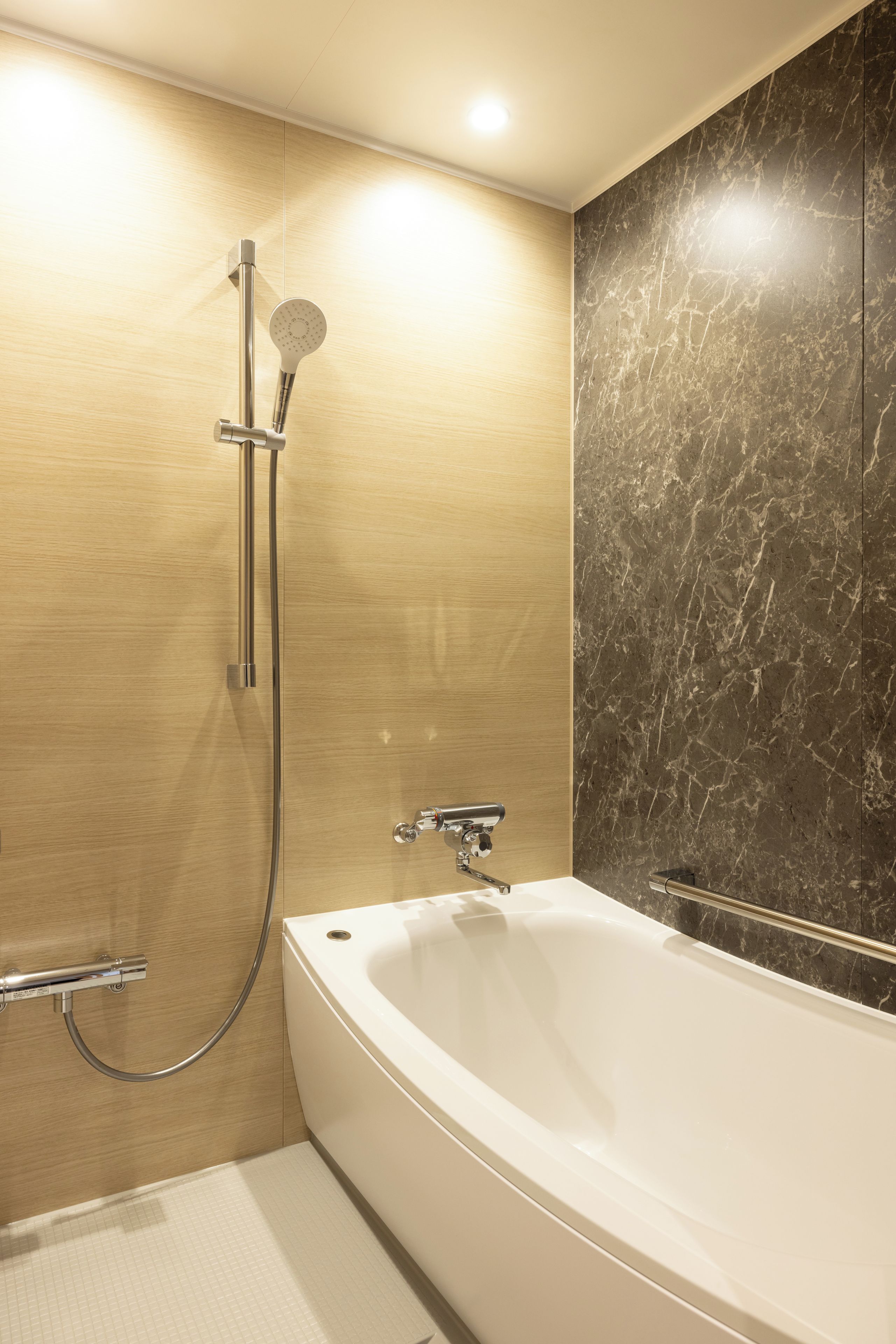 Un baño moderno con una bañera independiente, un cabezal de ducha manual y un grifo empotrado en la pared.