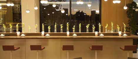 Un área de bar moderna con varias opciones de asientos, incluyendo taburetes y una mesa con un juego de té.