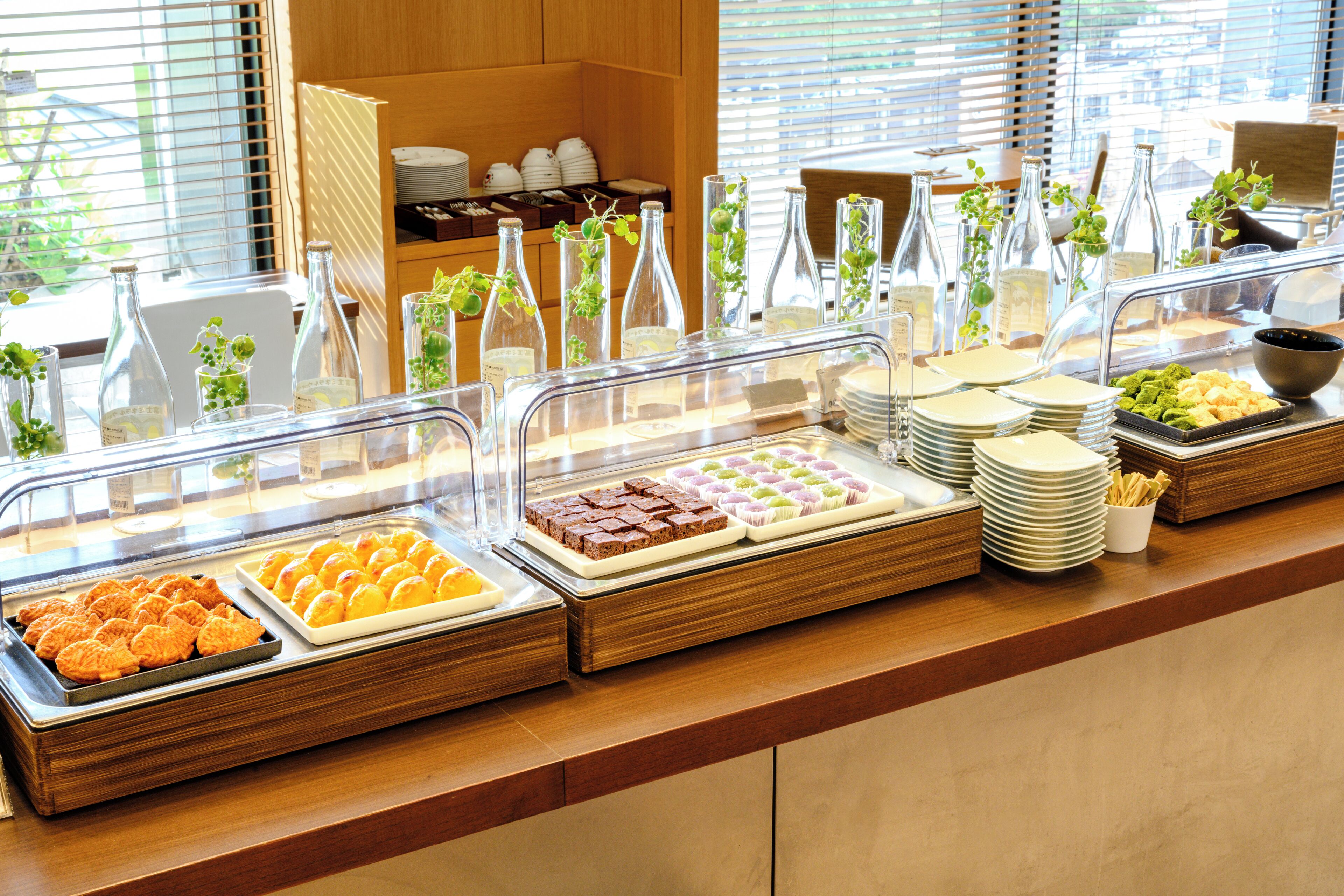 Een buffet met diverse gerechten en glazen flessen met planten.