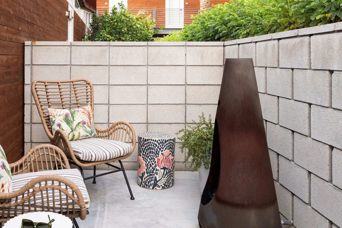 A patio area with wicker chairs, a round table, and a decorative metal sculpture.
