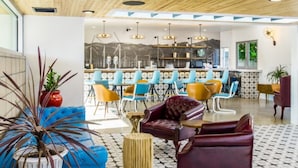 A modern interior with a bar area, seating, and a large potted plant. - ARRIVE Palm Springs - Adults Only (Palm Springs)