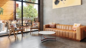 A modern lounge area with a leather sofa, round tables, and wicker chairs. - ARRIVE Palm Springs - Adults Only (Palm Springs)
