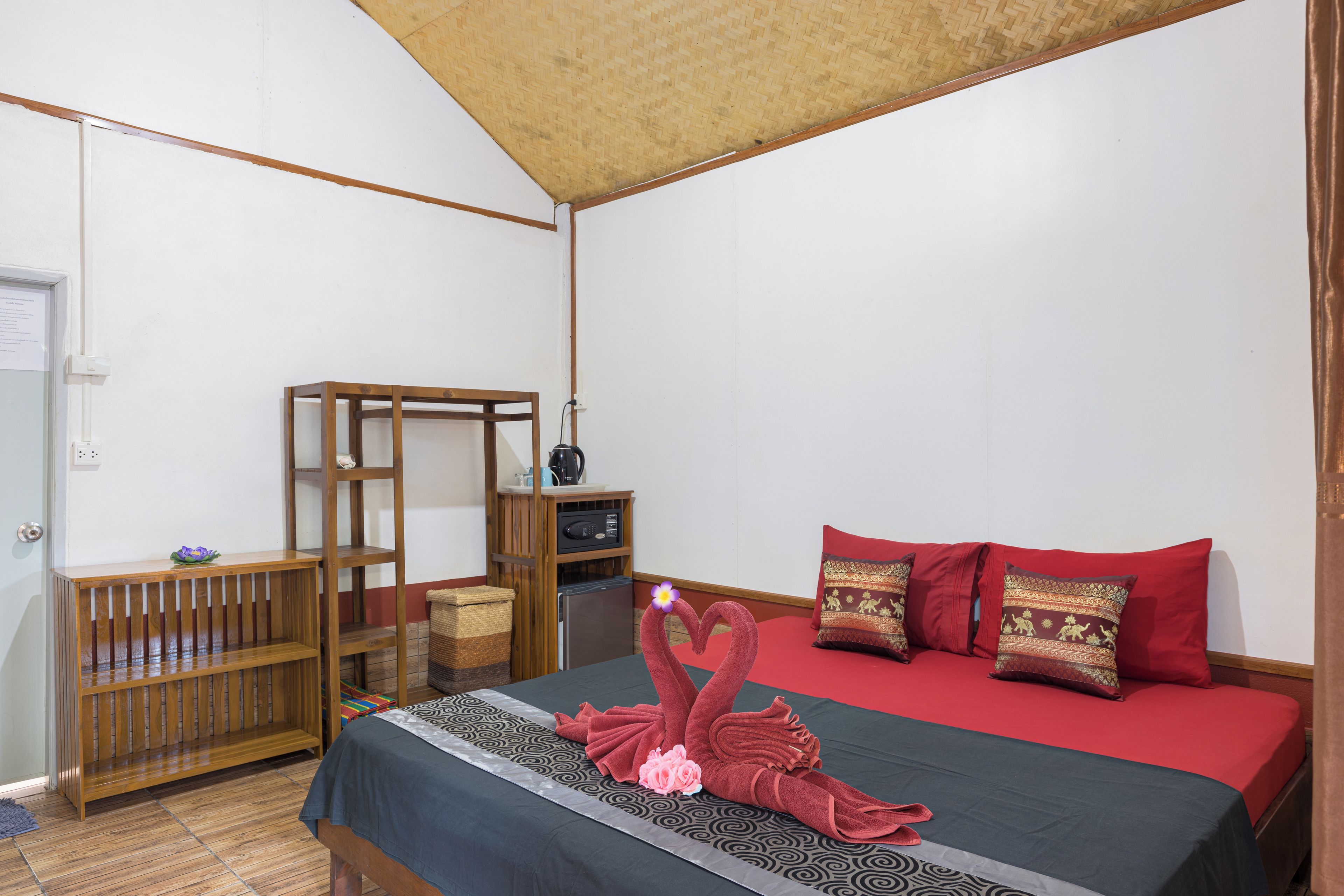 A room with a bed, a wooden shelf, a small table, and a red sofa.