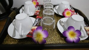 A tray with white teacups, saucers, and a glass of iced tea, along with packets of Nescafé coffee and a purple flower. - Family Song Koh Lipe (Koh Lipe)