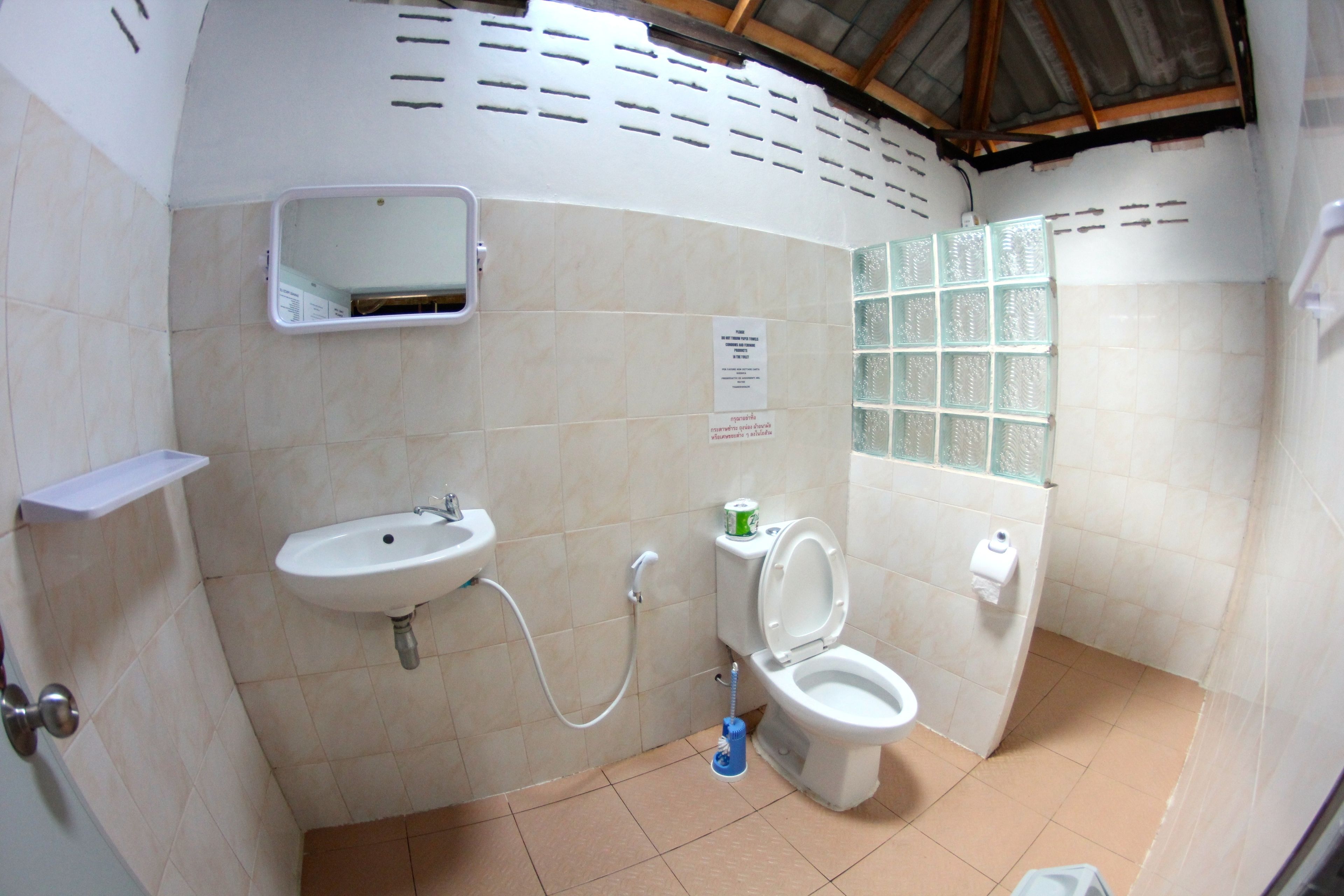 Et lille badeværelse med vask, toilet og spejl.