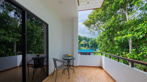 A balcony with a wooden floor, a glass door, and a table with two chairs. - Family Song Bungalow (Koh Lipe)