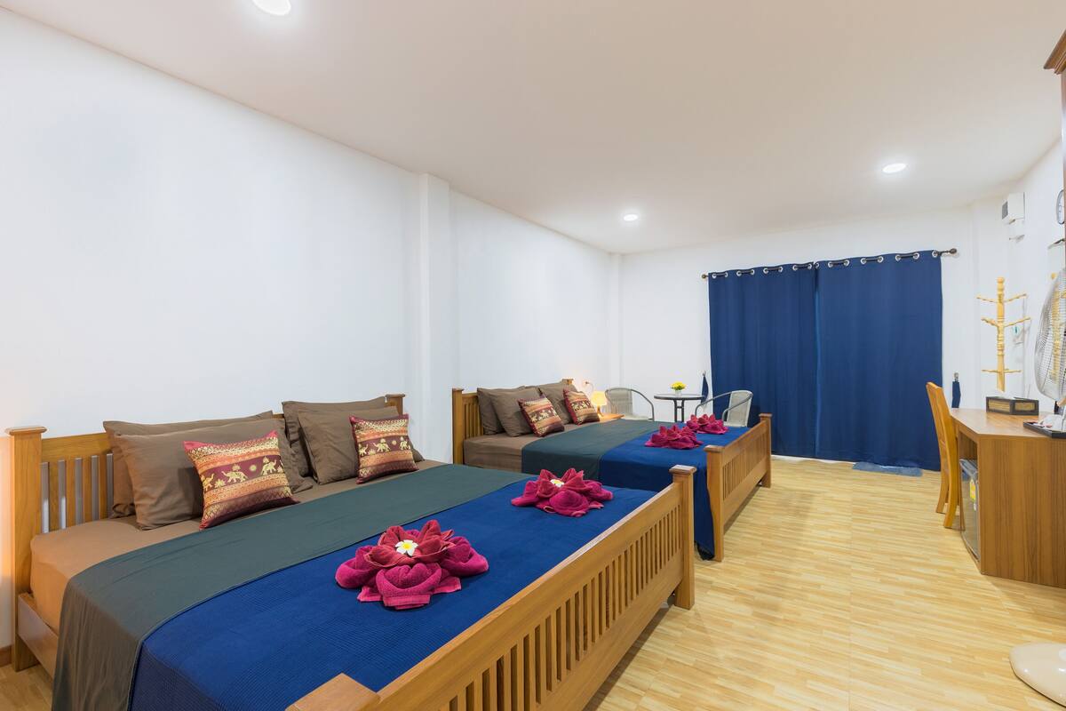 A hotel room with two beds, wooden headboards, and a small desk with a chair.