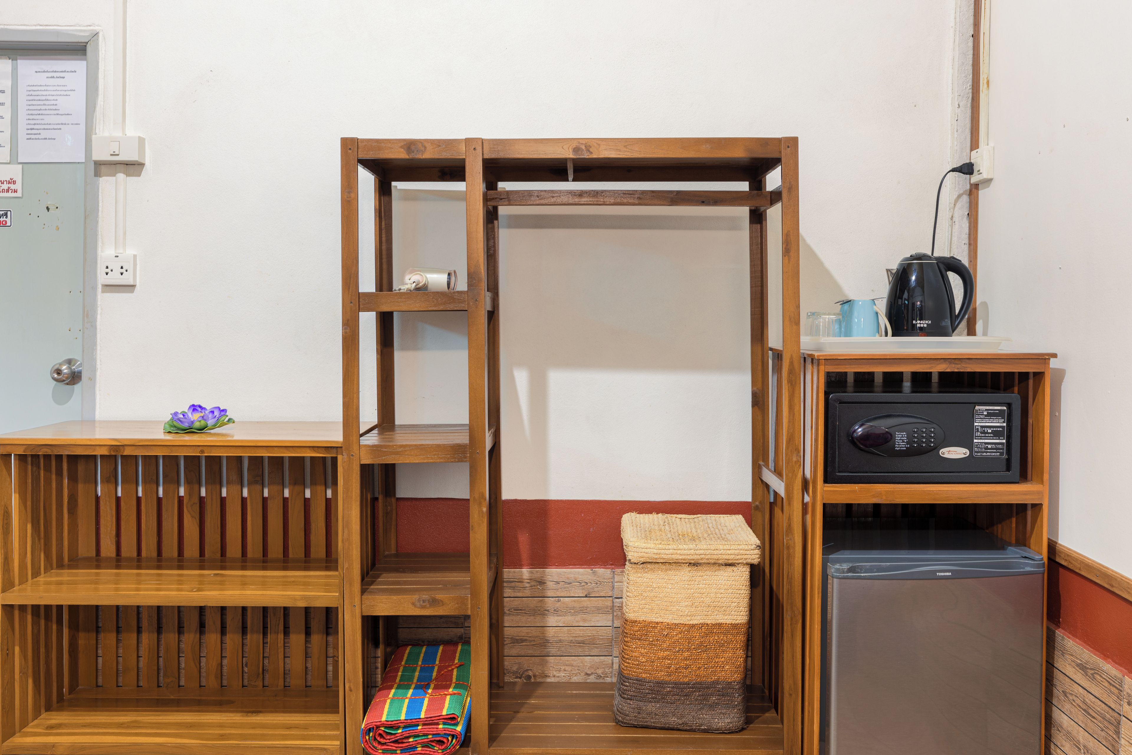 A compact room with a wooden bench, a small table with a vase, a refrigerator, and a microwave.