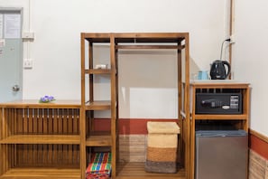 A compact room with a wooden bench, a small table with a vase, a refrigerator, and a microwave.