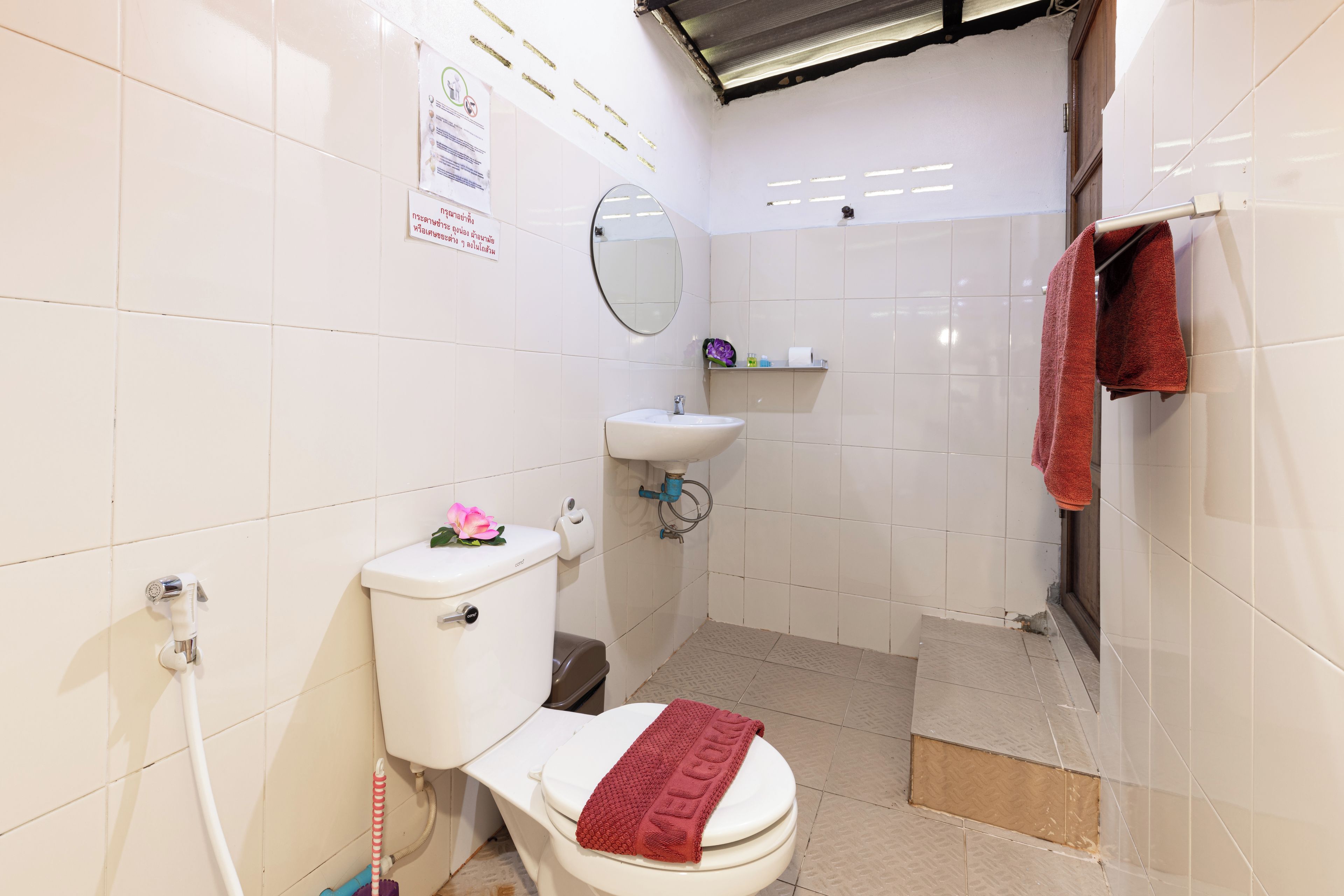 A bathroom with a toilet, sink, mirror, and shower area.