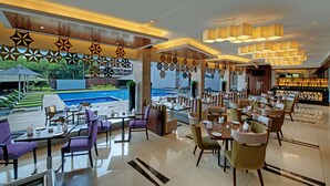 A modern restaurant with a pool view, featuring a mix of seating areas and a bar. - The Fern Kadamba Hotel & Spa Goa, Panjim, Series by Marriott (Panaji)