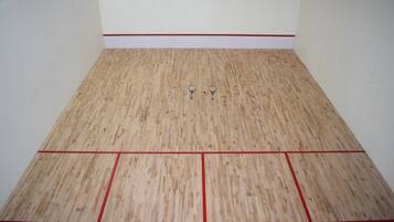 A squash court with a wooden floor and red lines marking the boundaries.