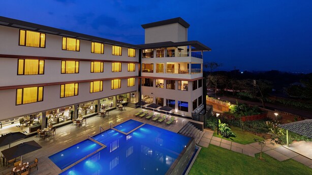 A multi-story hotel with a pool area, outdoor seating, and a view of the surrounding landscape. - The Fern Kadamba Hotel & Spa Goa, Panjim, Series by Marriott (Panaji)