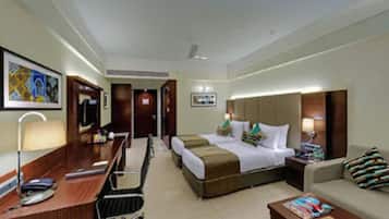 Habitación de hotel con cama, escritorio, silla, sofá y televisor.