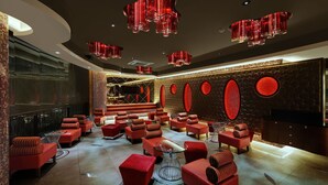 A modern lounge area with red seating, a bar, and decorative lighting. - The Fern Kadamba Hotel & Spa Goa, Panjim, Series by Marriott (Panaji)