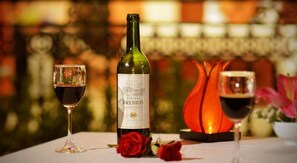A bottle of Chateau Brebion Bordeaux wine, a glass of wine, and a candle on a table with a blurred background. - Rice Village Homestay (Da Nang)